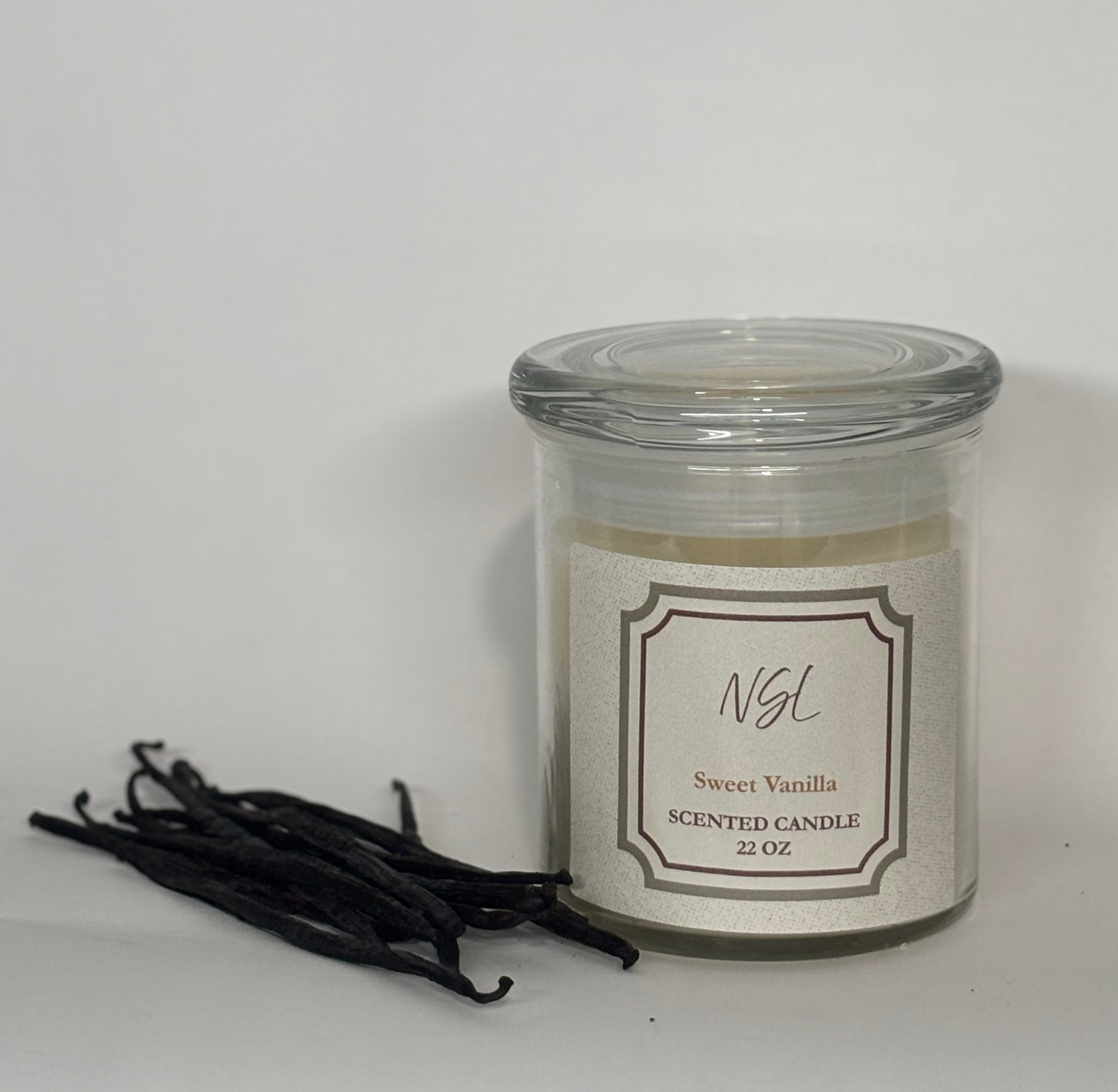 Scented candle labeled sweet vanilla with vanilla beans on a white background