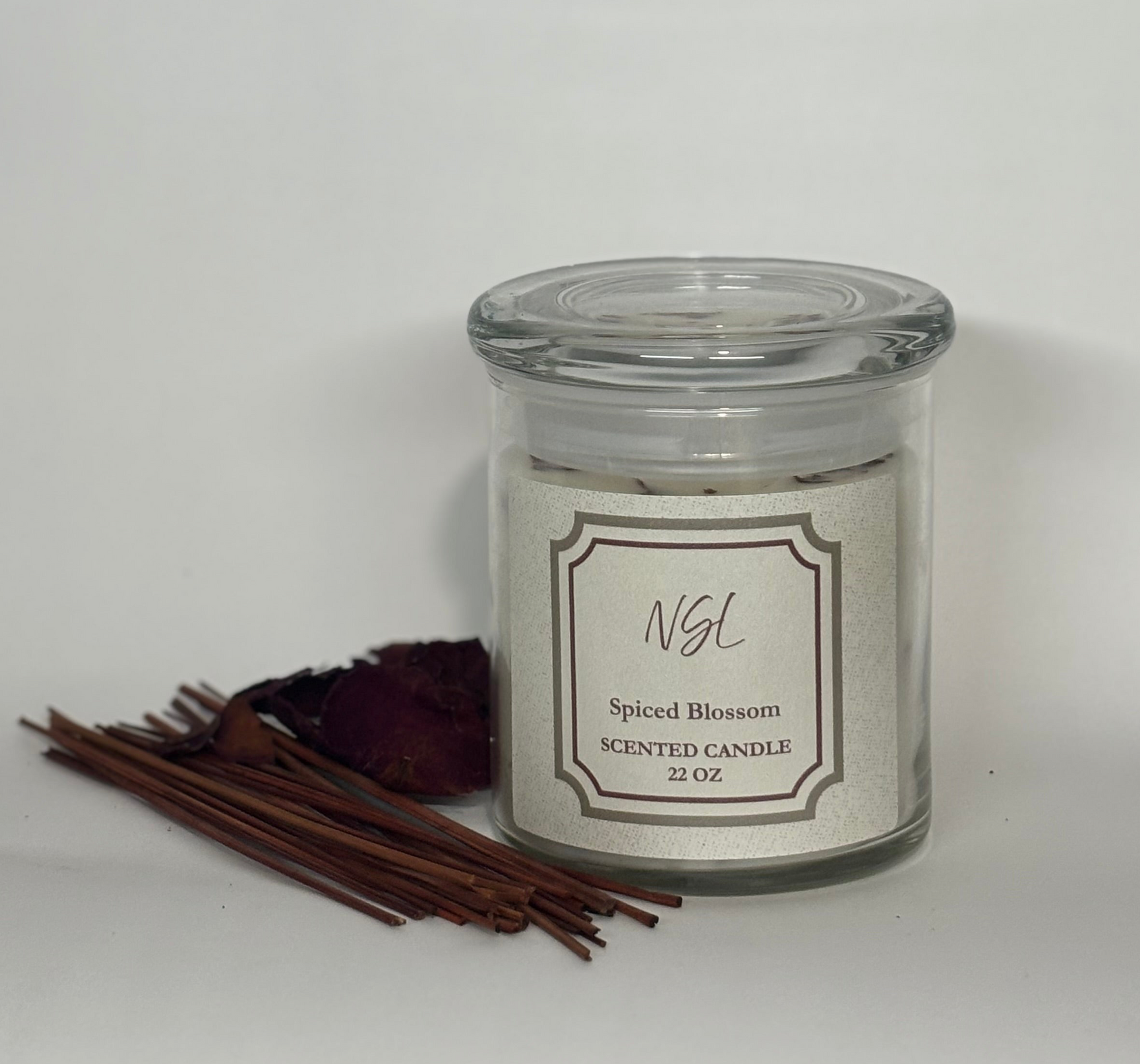 Scented candle labeled 'Spiced Blossom' with cinnamon sticks on a white background