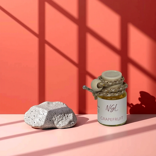 Grapefruit hanging diffuser on a red wall and pinkish table next to a rock